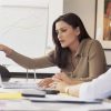 Woman holding top of laptop screen looking concerned